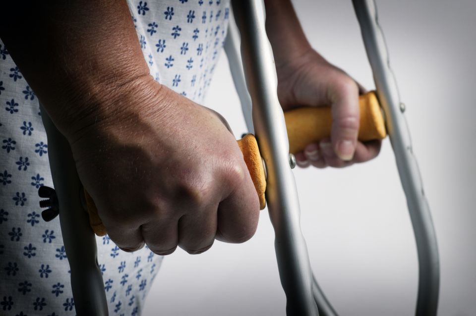 Someone gripping the handles of crutches, with part of their forearms and hands visible.