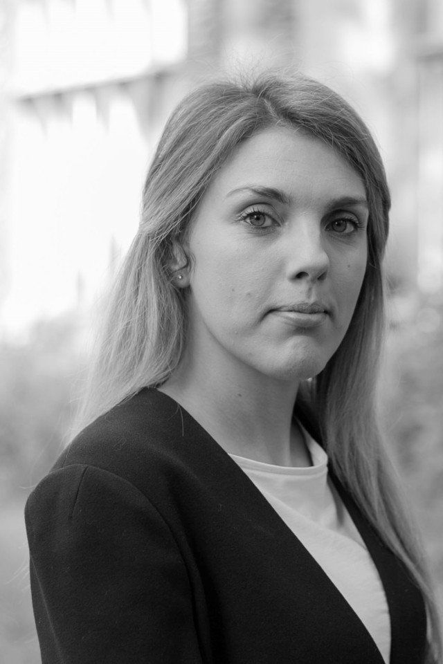 A black and white portrait of a woman with long hair, gazing directly at the camera.
